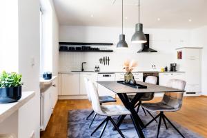 una cocina con armarios blancos, mesa negra y sillas en stycoz: Modernes Loft in der historischen Altstadt Memmingen en Memmingen
