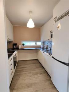 a kitchen with white cabinets and a refrigerator at Kotimaailma - Tyylikäs 3MH asunto Espoossa in Espoo