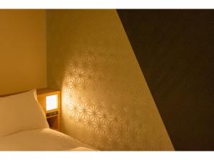 een slaapkamer met een bed en een muur bij Hotel Kanazawa in Kanazawa