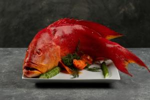 un pesce rosso seduto su un piatto con verdure di Villa Thamburu, Bentota a Bentota