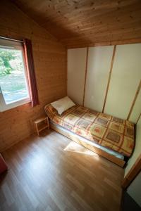 a small bedroom with a bed in a cabin at Le Pas de L'Ours in Aston