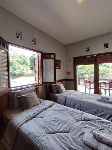 two beds in a room with two windows at Dalem Arum (for women only) in Bandung