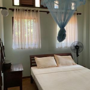 a bedroom with a bed with a blue curtain and a window at Lihini cottage in Galle +38 photos
