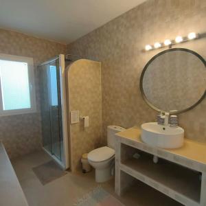Un baño con inodoro, lavabo y espejo. en La Finca de Véro, en Barbate