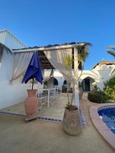 a patio with a blue umbrella and a pool at Dar Aladin in Arkou