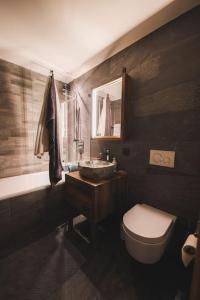 a bathroom with a toilet and a sink and a tub at Cosy, stylish new 2-bedroom flat with spa and gym in Laax