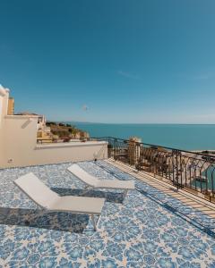 a balcony with two lounge chairs and the ocean at Domus Maris Relais Boutique Hotel in Sciacca