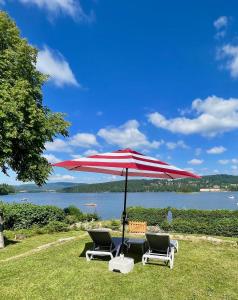 2 chaises et un parasol rouge et blanc sur l'herbe dans l'établissement Lipno Villa Beach - Lipno Stausee - Lakeside, à Loučovice