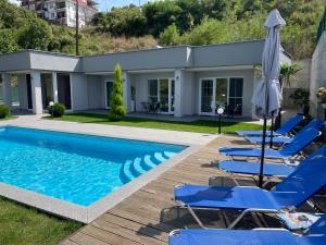 einen Pool mit blauen Stühlen und einem Sonnenschirm in der Unterkunft Villa Dimo Topal in Ohrid