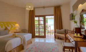 a bedroom with a bed and a desk and a window at Neptune Village Beach Resort & Spa - All Inclusive in Galu