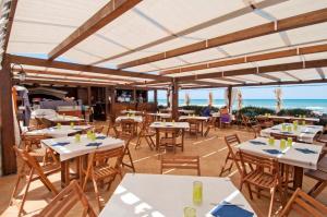um restaurante com mesas e cadeiras com o oceano ao fundo em Appartamento Blue Marine Residence - Rodi Garganico 37-38-39 settimana em Foce Varano