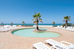 uma piscina com cadeiras e palmeiras e o oceano em Appartamento Blue Marine Residence - Rodi Garganico 37-38-39 settimana em Foce Varano