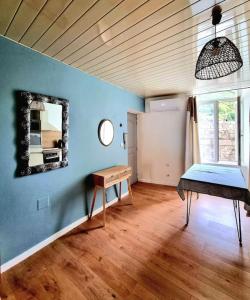 Habitación con paredes azules, espejo y mesa. en Les Hirondelles, charmant 2 pièces au coeur du village, en Anduze