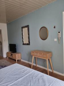 1 dormitorio con cama, espejo y mesa en Les Hirondelles, charmant 2 pièces au coeur du village, en Anduze