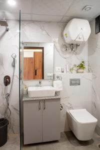 Baño blanco con lavabo y aseo en Perch Arbor Cyber City en Gurgaon