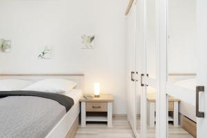 ein weißes Schlafzimmer mit einem Bett und einem Spiegel in der Unterkunft Belvedere Ostseebrise in Grömitz