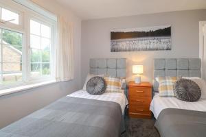 two beds in a bedroom with two windows at 83 Oaklands Road in Havant