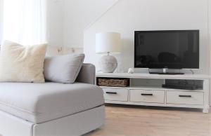 ein weißes Wohnzimmer mit einem Sofa und einem TV in der Unterkunft Oceanhouse in Olpenitz