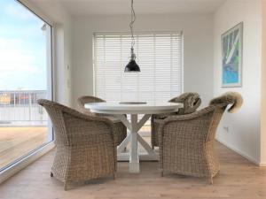 a dining room with a white table and wicker chairs at Oceanhouse in Olpenitz