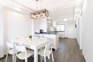 een keuken en eetkamer met een witte tafel en stoelen bij TuristMar - Fabuloso apartamento con vista de lujo in Salou