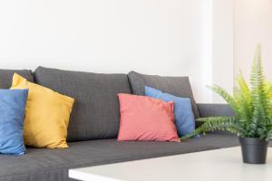een grijze bank met kleurrijke kussens erop bij TuristMar - Fabuloso apartamento con vista de lujo in Salou