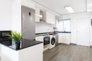 een keuken met witte apparatuur en een zwart aanrecht bij TuristMar - Fabuloso apartamento con vista de lujo in Salou