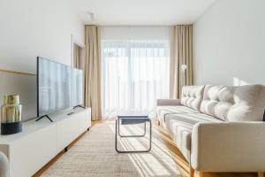 a living room with a white couch and a tv at Apartament SUN SurfingBird Dźwirzyno in Dźwirzyno