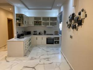 Appartement moderne et spacieux au coeur de Tanger في طنجة: مطبخ بدولاب بيضاء وأرضية من الرخام