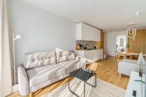 a living room with a white couch and a kitchen at Apartament SUN SurfingBird Dźwirzyno in Dźwirzyno