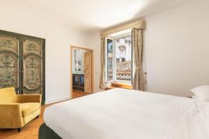 1 dormitorio con cama blanca, silla y ventana en Casa Colonna by Burghesius, en Roma