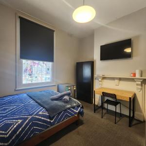 a bedroom with a bed and a desk and a television at 50 Green St Windsor in Melbourne