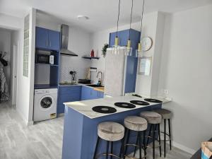 una cocina con armarios azules y una barra con taburetes en Increíble Apartamento de lujo en Triana, en Sevilla 11 fotos más