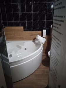 a white tub in a bathroom with a sign next to it at PANORAMA SPA apartman in Kraljevo