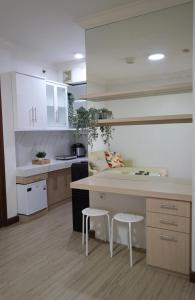 een keuken met witte kasten, een aanrecht en krukken bij Majesty Apartment 2 Bedroom with City View in Bandung