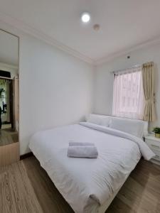 een witte slaapkamer met een groot wit bed en een raam bij Majesty Apartment 2 Bedroom with City View in Bandung