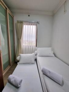twee bedden in een kleine kamer met een raam bij Majesty Apartment 2 Bedroom with City View in Bandung