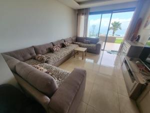 ein Wohnzimmer mit einem Sofa und einem Tisch in der Unterkunft Appartement Plage des Nations Prestigia Front Mer avec grand Jardin in Sidi Bouqnadel