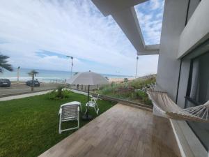 - une terrasse couverte avec un hamac, un parasol et l'océan dans l'établissement Appartement Plage des Nations Prestigia Front Mer avec grand Jardin, à Sidi Bouqnadel