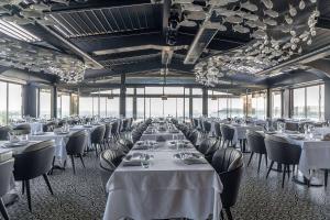 a restaurant with white tables and chairs and windows at Wyndham Grand Istanbul Kalamış Marina Hotel in Istanbul