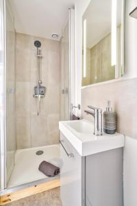 biała łazienka z umywalką i prysznicem w obiekcie Top Destination Pontoise w mieście Pontoise
