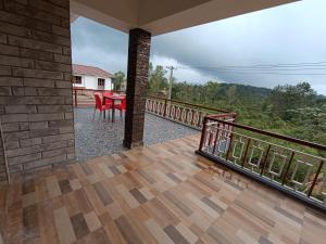 a balcony of a house with a table and chairs at Hill View Retreat - Coorg in Madikeri