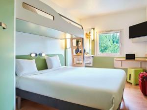 uma grande cama branca num quarto com uma janela em ibis budget Santeny em Santeny