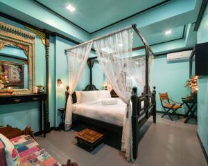 a bedroom with a canopy bed and a table at DE Phanakron Boutique Hotel in Bangkok
