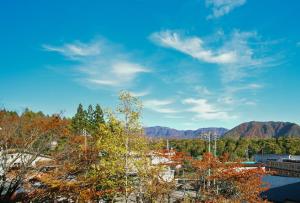 ein Blick vom Dach eines Gebäudes mit Bäumen und Bergen in der Unterkunft 栂池高原　丘の上ホテル in Otari
