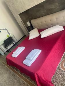un grande letto rosso con due asciugamani bianchi di Centro da Marco a Savona