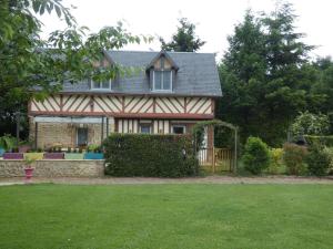 una casa con un patio verde con una valla y un patio Sidx Sidx en Gîte Les Ronces, en Conteville
