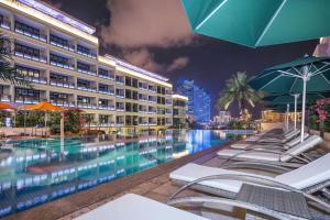 una piscina de hotel con sillas y sombrillas por la noche en Wingate by Wyndham Sanya Luhuitou en Sanya