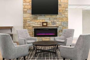 a waiting room with chairs and a table and a fireplace at AmericInn by Wyndham La Crosse Riverfront Conference Center in La Crosse
