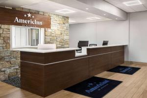 an office with a reception desk and a stone wall at AmericInn by Wyndham La Crosse Riverfront Conference Center in La Crosse