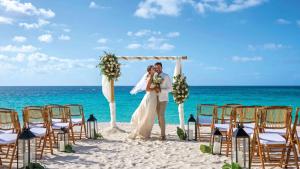 a bride and groom standing under a wedding arch on the beach at Zemi Beach House, LXR Hotels & Resorts in Shoal Bay Village